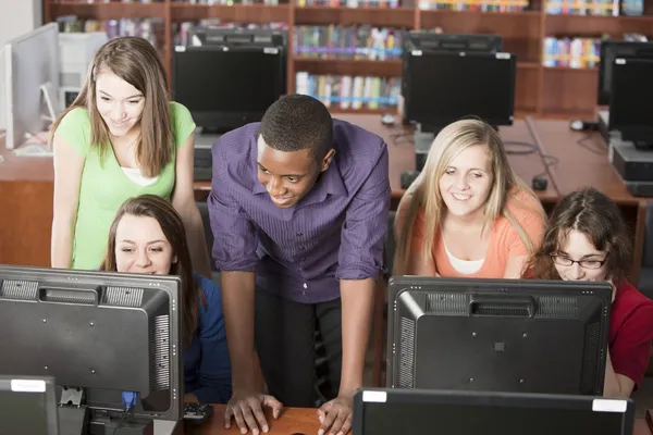 Educación. Grupo de estudiantes adolescentes de secundaria trabajando juntos usando computadoras en la biblioteca de la escuela —  Fotos de Stock