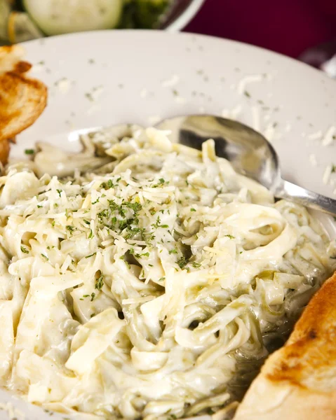 Essen und Trinken. Nahaufnahme Bild eines reichen, cremigen fettucini alfredo Abendessen mit Knoblauchbrot — Stockfoto