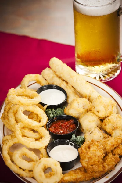 Food and Drink. Appetizer with a variety of fried foods such as onion rings, chicken strips and fried cheese with a frosty mug of beer — Stock Photo, Image
