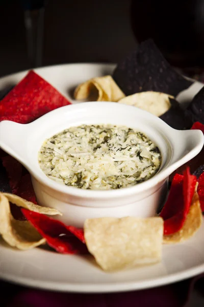 Essen und Trinken. eine Vorspeise aus käsigem Spinat und Artischocken-Dip mit Tortilla-Chips — Stockfoto