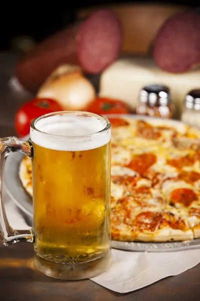 Comida y bebida. Una pizza de carne picante con una jarra fría de cerveza . — Foto de Stock