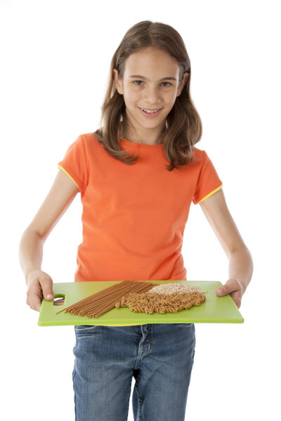 Здоровое питание. Кавказская маленькая девочка держит поднос с зерном с расположением макарон и риса
