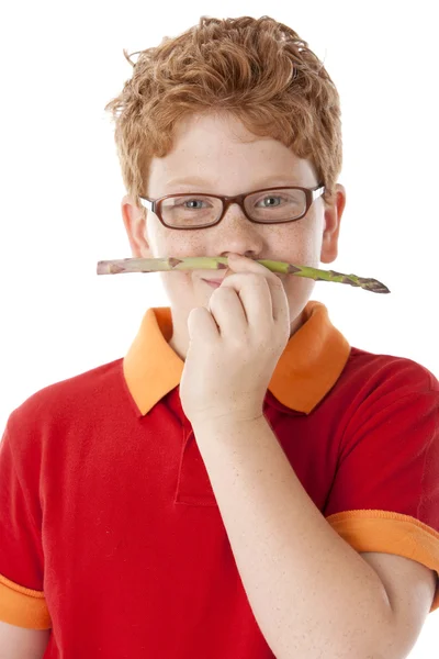 Gezond eten. Kaukasische kleine jongen houdt een stuk van asperge tot zijn mond als een snor — Stockfoto