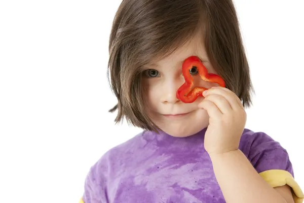 Healthy Eating. Caucasian little girl holding a red pepper in front of her eye — Stock Photo, Image