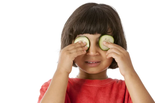 Gezond eten. gemengd ras weinig meisje bedrijf komkommers over haar ogen — Stockfoto