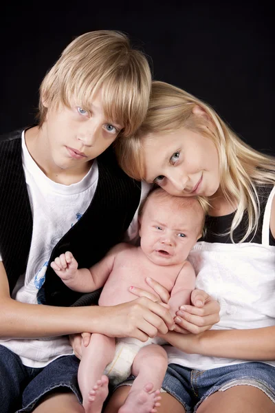 Prawdziwe. Pokój typu Twin brat i siostra trzyma ich jednego miesiąca życia noworodka chłopiec kuzyn — Zdjęcie stockowe