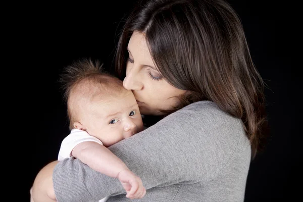 A sério. caucasiano mãe segurando e beijando ela um mês de idade recém-nascido menino — Fotografia de Stock