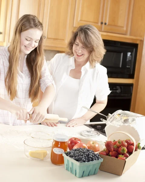 Sütés. Kaukázusi anya és lánya, a konyhában dagasztása tészta, készítsünk egy gyümölcs desszert — Stock Fotó