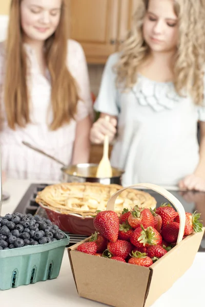 Baking. Caucasian teenage girlfriends making a fruit pie with homegrown fruits in the kitchen — Stock Photo, Image