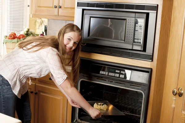 Horneando. Caucásico adolescente poniendo un pastel de frutas en el horno . — Foto de Stock