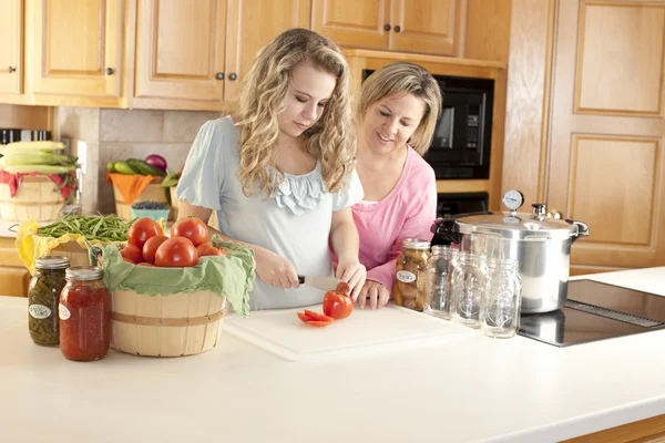 Canning. Mãe branca ajudando sua filha adolescente pode frutas e legumes caseiros — Fotografia de Stock