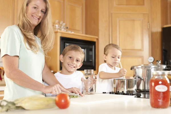Каннинг. Мать и два ее сына консервируют домашние фрукты и овощи — стоковое фото