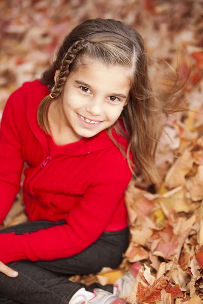 Smiling caucasian little girl in the seasonal autumn leaves — Stock Photo, Image