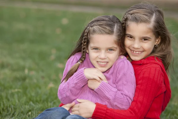 Smiling caucasian little girl sisters sitting togetter outdoors — Stock Photo, Image
