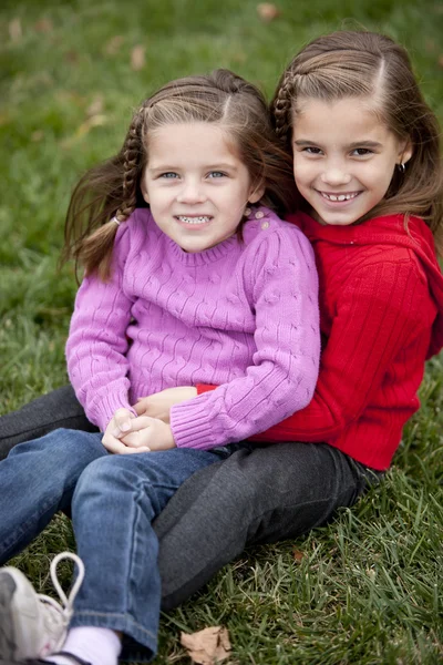 Sorrindo caucasiano meninas irmãs sentadas togetter ao ar livre — Fotografia de Stock