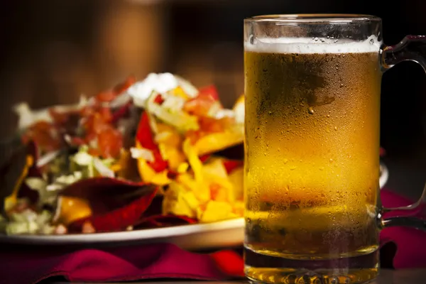 Essen und Trinken. eine Nahaufnahme von würzigen Nachos mit einem kalten, frostigen Becher Bier. lizenzfreie Stockfotos