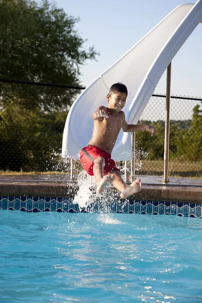 Nuoto estivo. Piccolo ragazzo ispanico che si diverte al sole estivo su uno scivolo d'acqua Immagini Stock Royalty Free