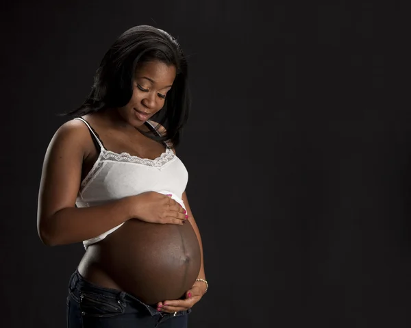 Real. Black expectant mother tenderly holding her abdomen Royalty Free Stock Photos