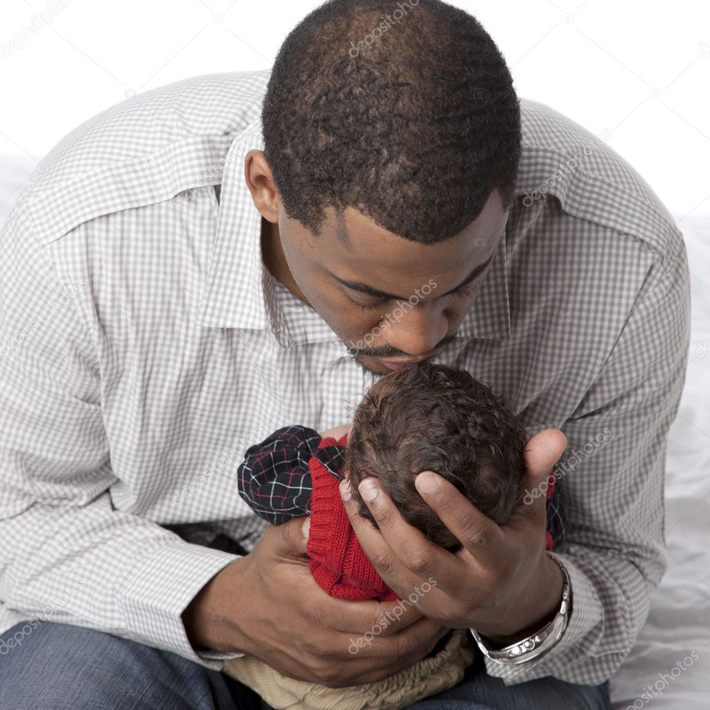 African american father kissing his newborn baby son