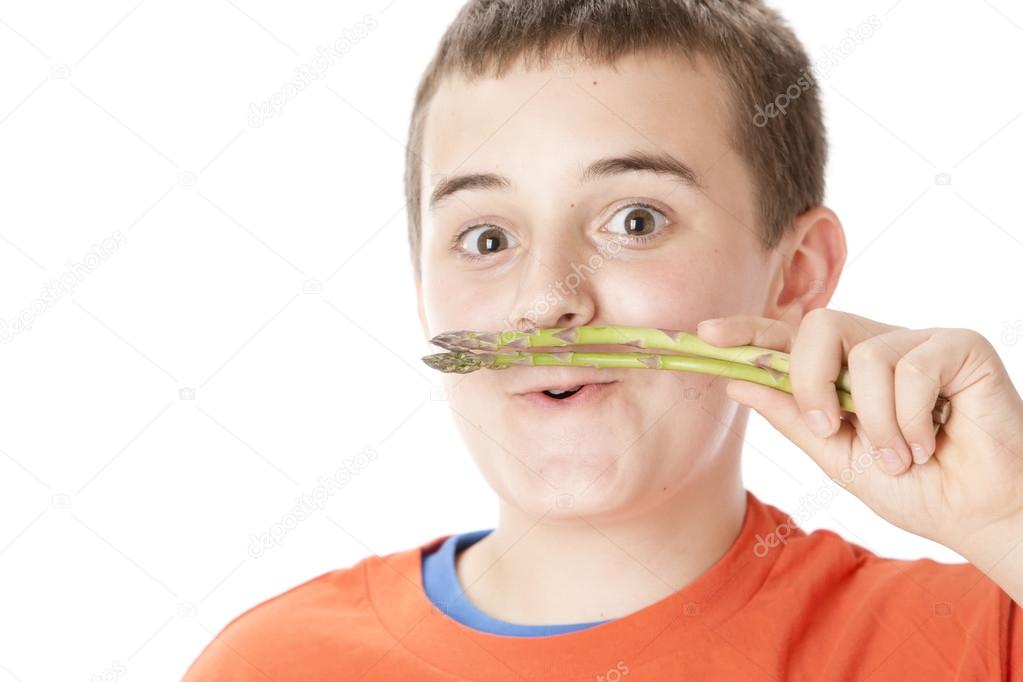 Healthy Eating. Caucasian boy holding asparagus to his mouth like a moustache