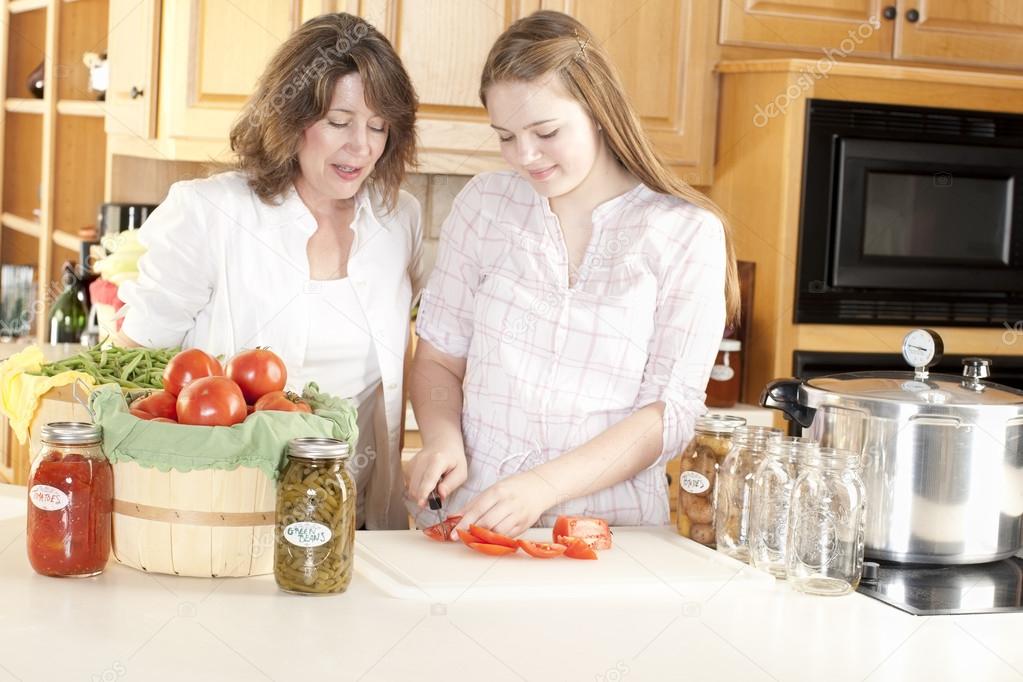 Canning. Caucasian mother helping her teenage daughter can homegrown fruits and vegetables