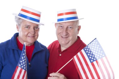 Amerikan bayrakları sallayarak ve yıldızlar ve çizgiler ile şapka giymiş kıdemli yetişkin vatansever Çift