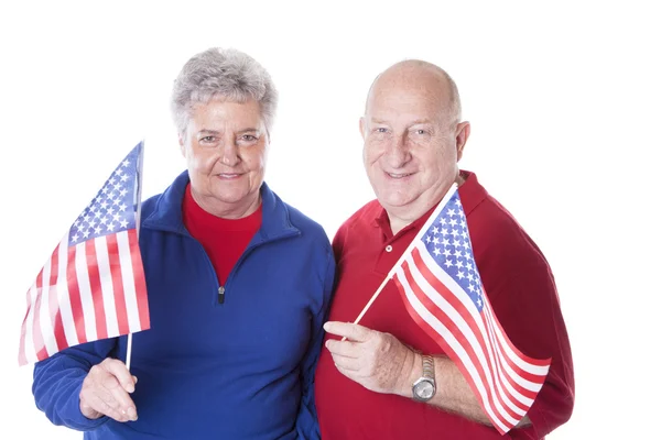 Casal patriótico adulto caucasiano acenando com bandeiras americanas e usando chapéus com estrelas e listras — Fotografia de Stock