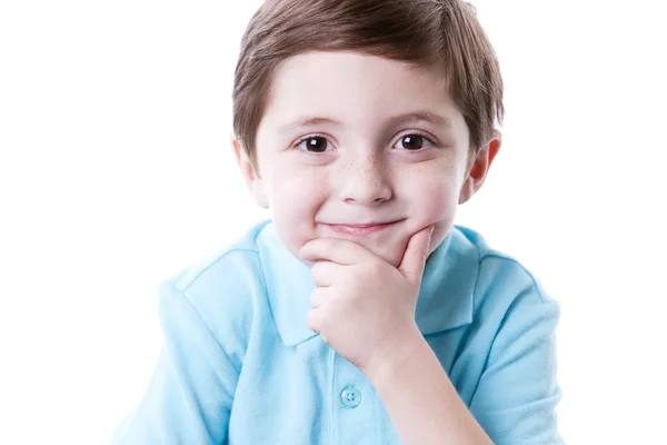 Sonriente contenido caucásico pequeño niño de verdad con la mano en la barbilla como si estuviera pensando . — Foto de Stock