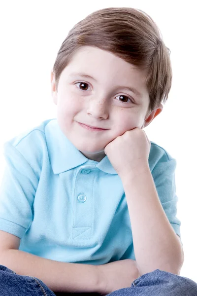 Sonriente contenido caucásico pequeño niño de verdad con la mano en la barbilla como si estuviera pensando . — Foto de Stock