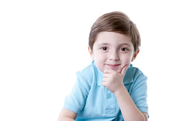 Sonriente contenido caucásico pequeño niño de verdad con la mano en la barbilla como si estuviera pensando . — Foto de Stock