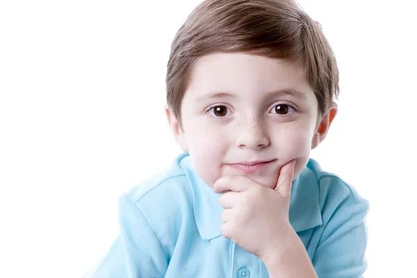 Sonriente contenido caucásico pequeño niño de verdad con la mano en la barbilla como si estuviera pensando . — Foto de Stock