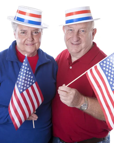 Caucasian senior adult patriotic couple waving american flags and wearing hats with stars and stripes Royalty Free Stock Photos