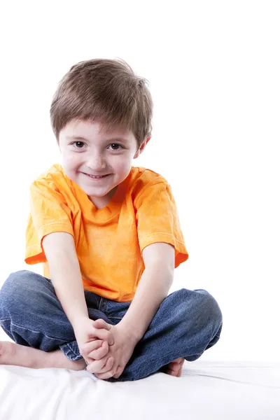Sorrindo caucasiano menino sentado de pernas cruzadas — Fotografia de Stock