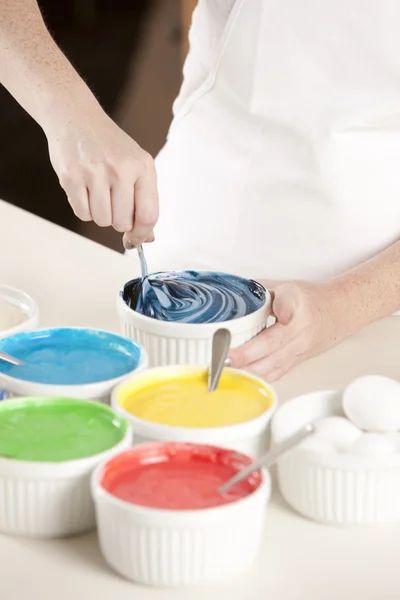 Un gâteau arc-en-ciel. chef mélange la pâte colorée pour préparer les couches pour le dessert — Photo