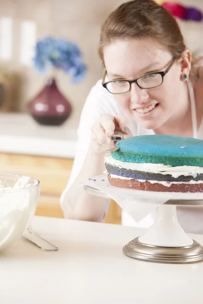 Un gâteau arc-en-ciel. Un chef met du glaçage sur le dessert coloré — Photo
