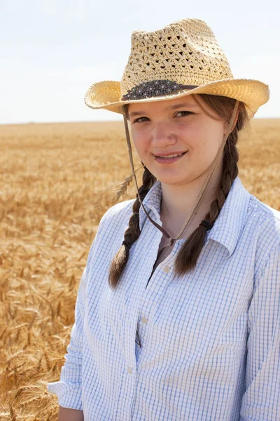 Unga midwestern cowgirl står vete fältet på gården — Stockfoto