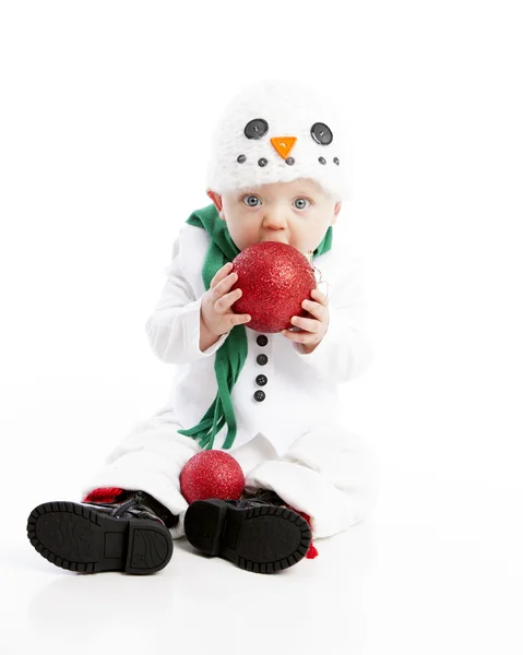 Teething baby boy dressed in snowman costume chews christmas ornament — Stock Photo, Image