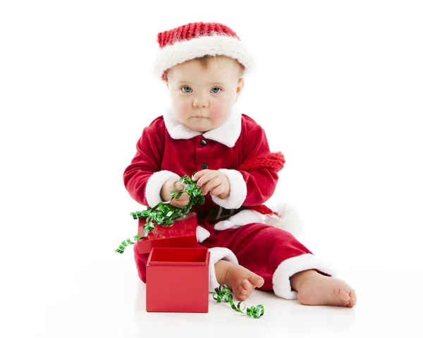 Funny baby girl opens a christmas present and makes a mess — Stock Photo, Image