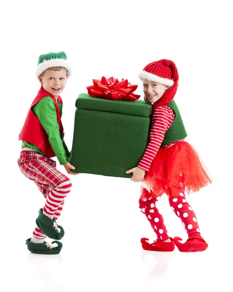 Two young elves struggle carrying a big, heavy, wrapped present. — Stock Photo, Image