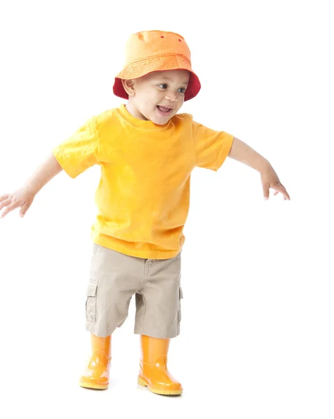 Niño afroamericano vistiendo un sombrero naranja brillante y galoshes Imagen de archivo