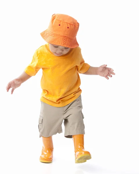 Niño afroamericano vistiendo un sombrero naranja brillante y galoshes Imagen De Stock