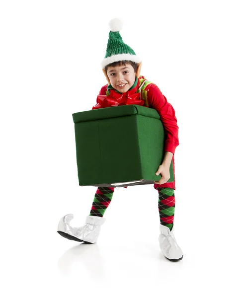 En spansktalande elf, kämpar med en stor, tung julklapp. Stockbild