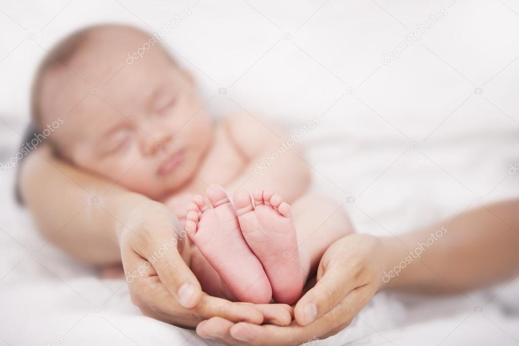 Hands holding peaceful sleeping caucasian newborn baby girl