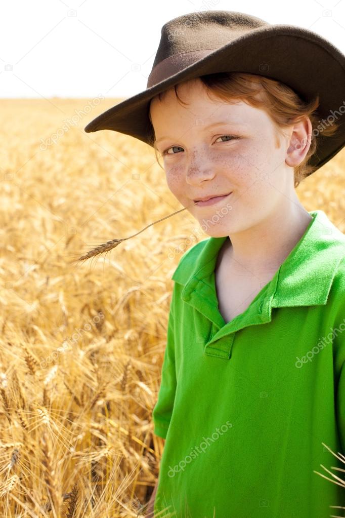 Young midwestern cowboy stands in wheat field on farm