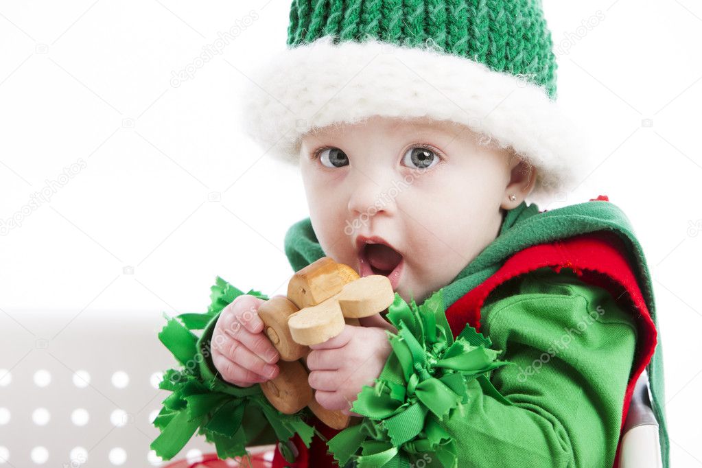 Caucasian baby girl chews on a wooden toy