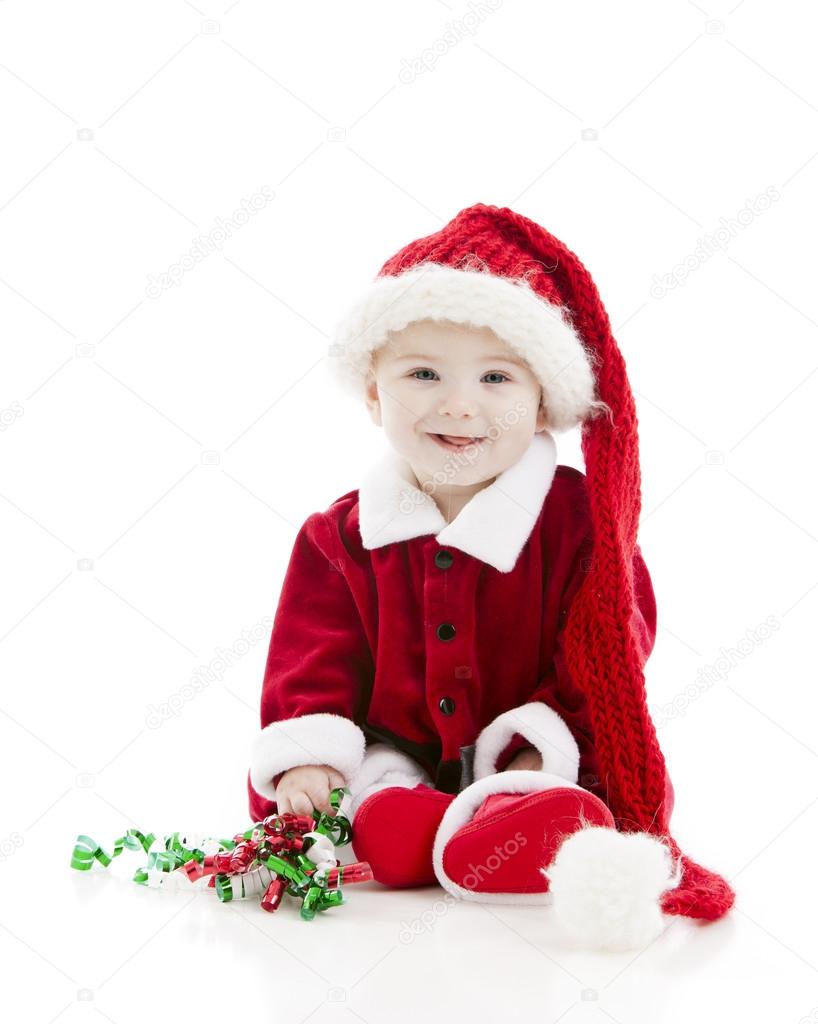 Little baby boy dressed as santa claus plays with christmas ribbon.