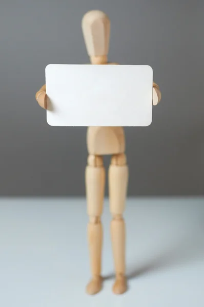 Wooden man holding empty white blank card for your text — Stock Photo, Image