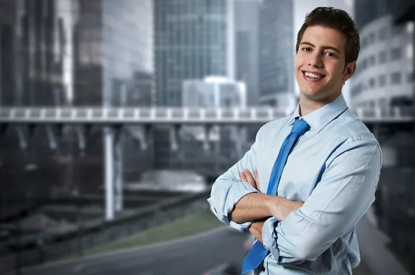 Succesvolle zakenman met kantoorgebouwen in de achtergrond — Stockfoto