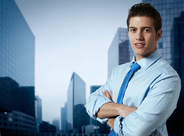 Succesvolle zakenman met kantoorgebouwen in de achtergrond — Stockfoto