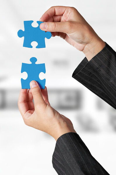 Концепция бизнеса: рука, держащая два кусочка головоломки
